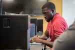 David Osafo, NSWC PCD engineer examines a virtual machine for possible vulnerabilities during the virtual 2021 HACKtheMACHINE challenge at Gulf Coast State College.