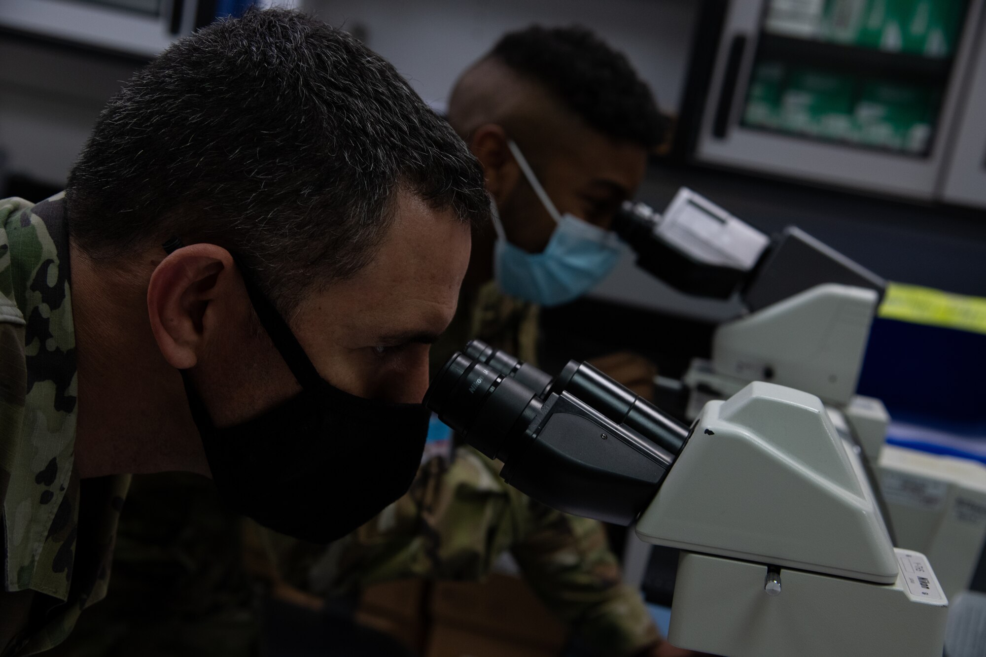 Two men look into microscope