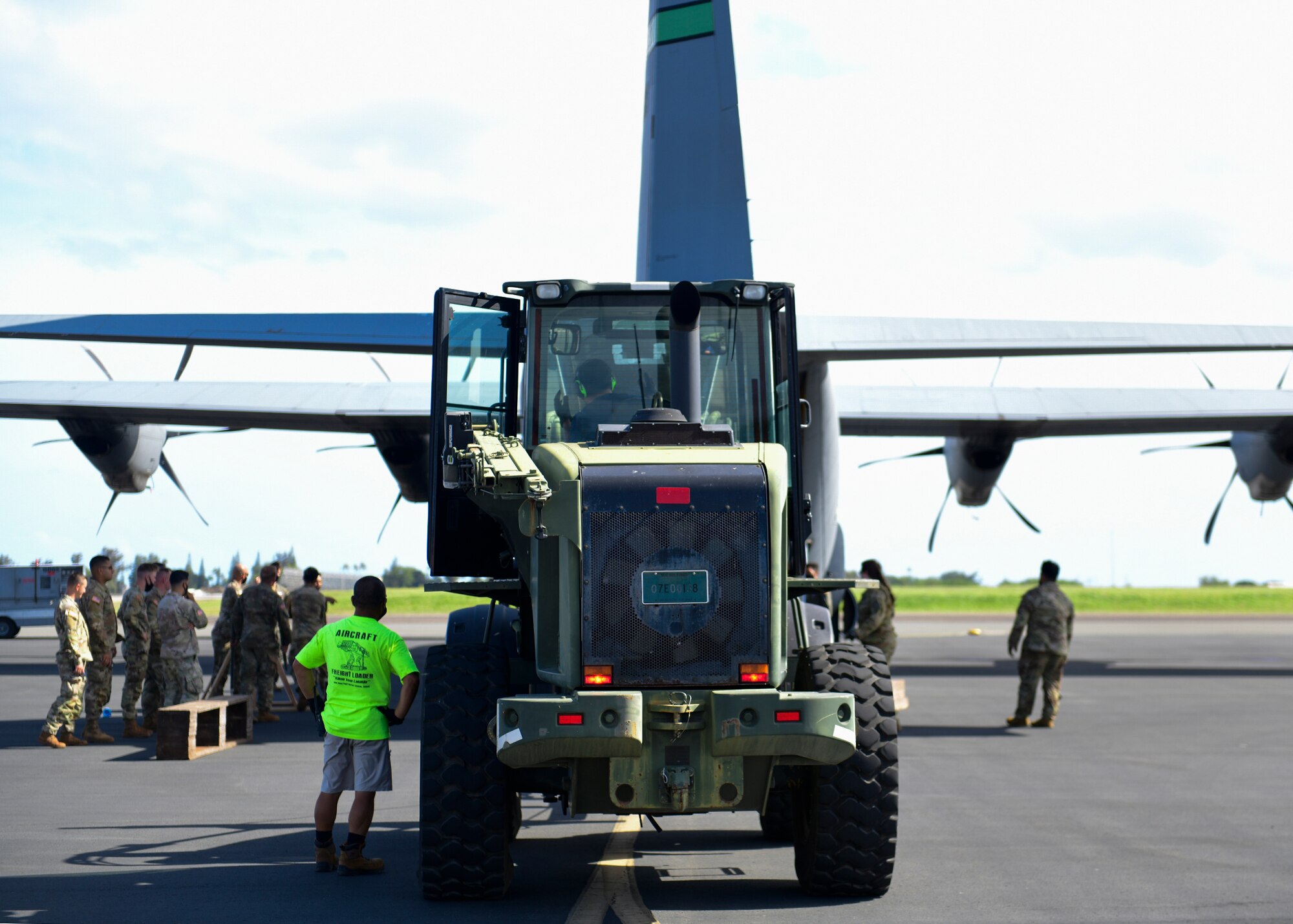 A forklift carries a M119 howitzer onto an aircraft