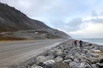 Two people walk on a seawall.