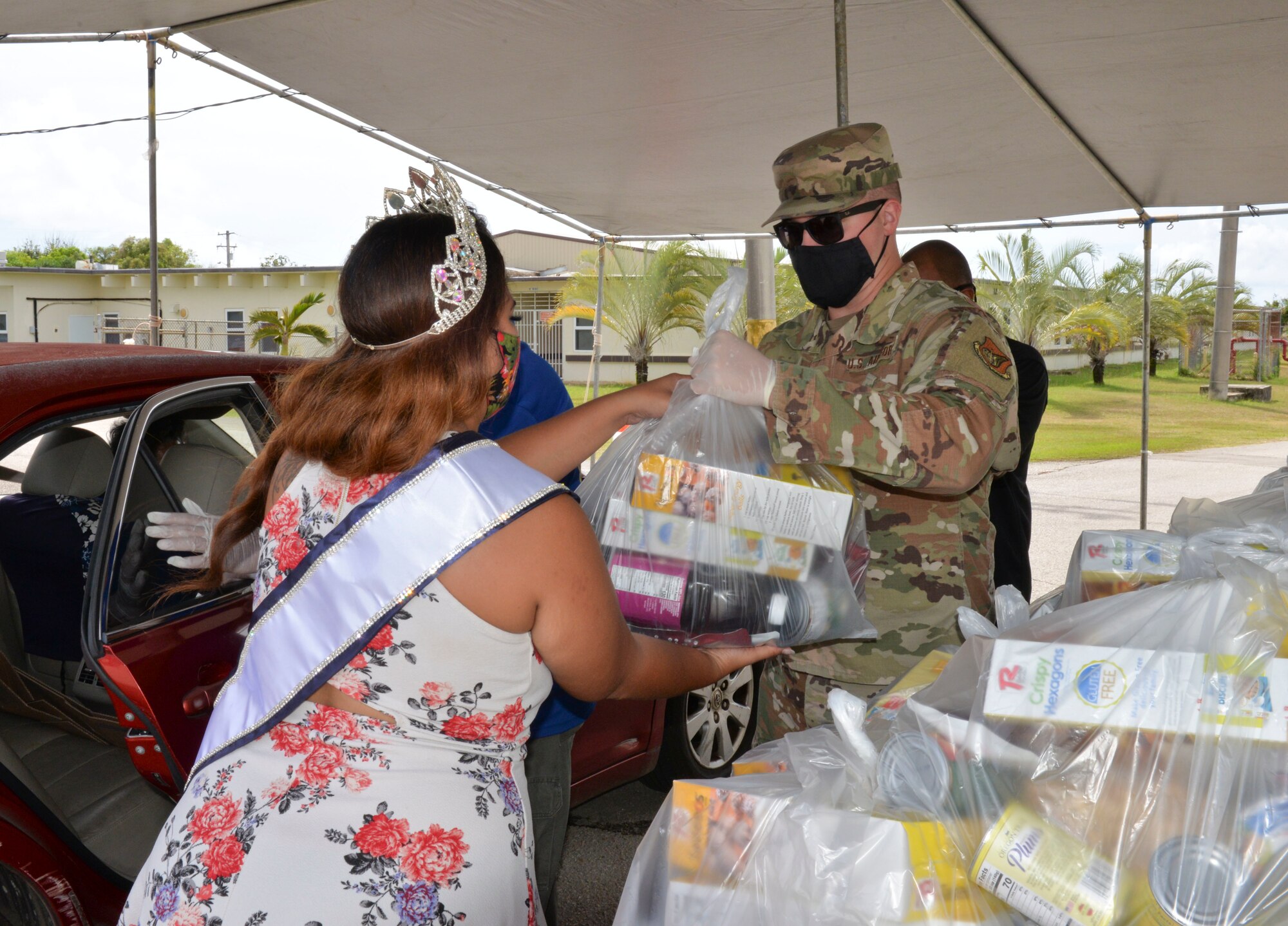 U.S. Air Force Staff Sgt. Nicholas Killian, 36th Civil Engineering Squadron workforce manager, hands a bag of food commodities to Kylani Ogo, Miss Voluptuous Pacific and Yona resident, during a COVID-19 relief food distribution event at the community gym in Yona, Guam, April 15, 2021. The 36th CES is Yona’s sister squadron, as part of the Andersen Air Force Base Sister Village Sister Squadron program, through which squadron members collaborate with Guam residents in activities to strengthen their friendship and partnership. (U.S. Air Force photo by Alana Chargualaf)