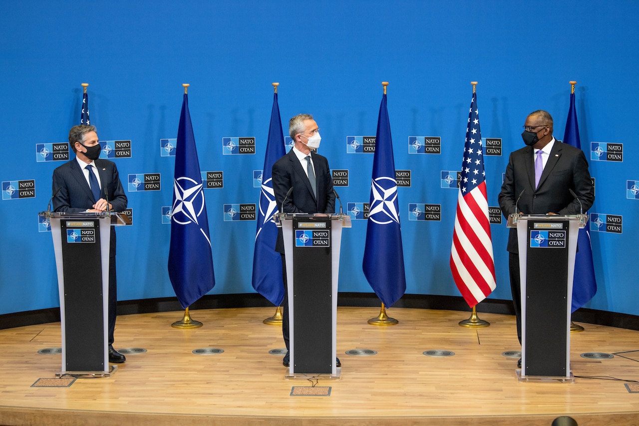 Three men stand on a stage.