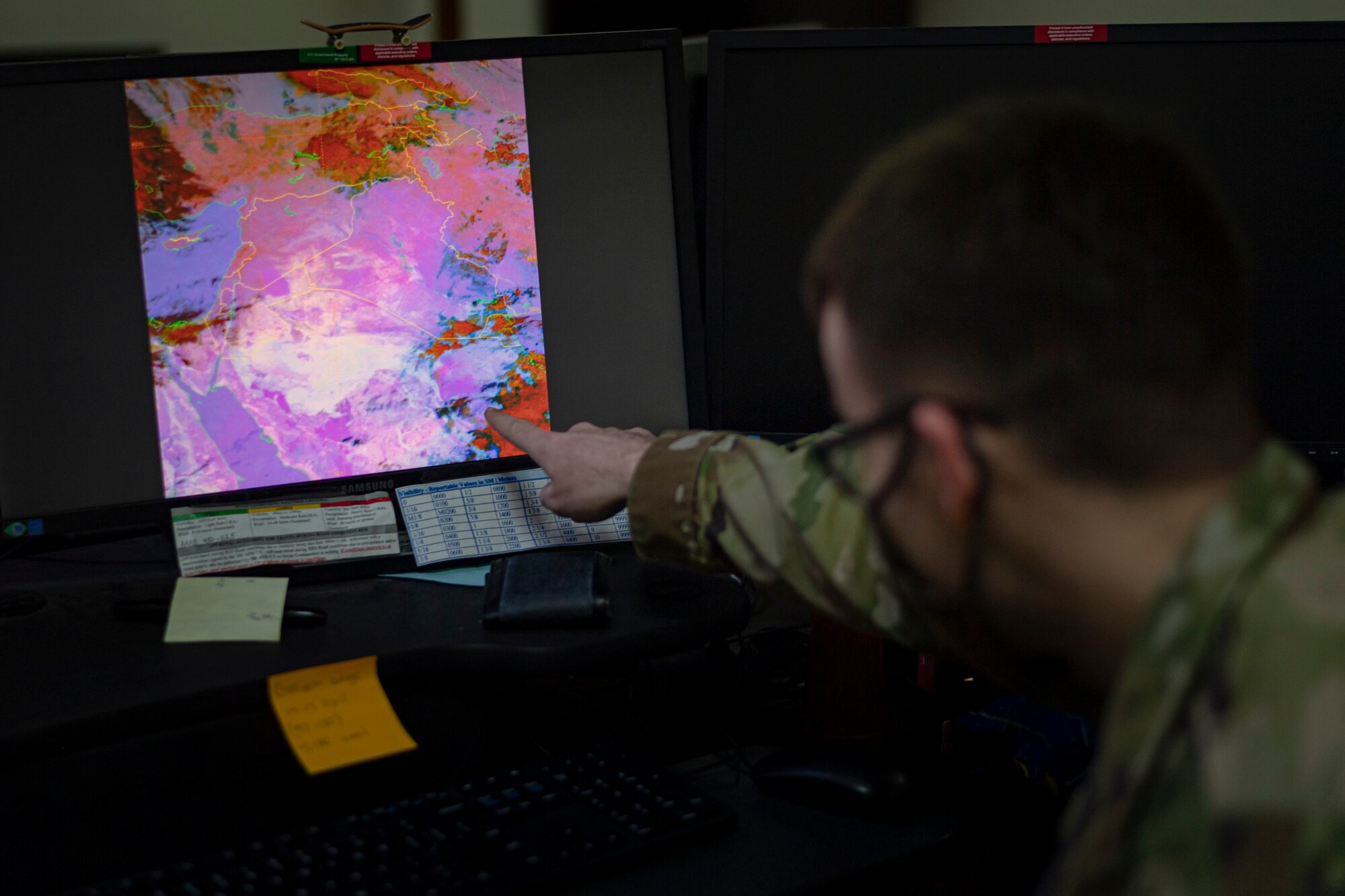 A photo of an Airman pointing at a computer