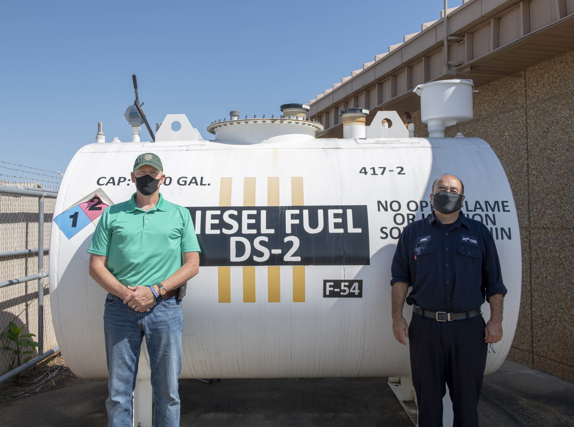 Photo of two people in front of fuel tank.