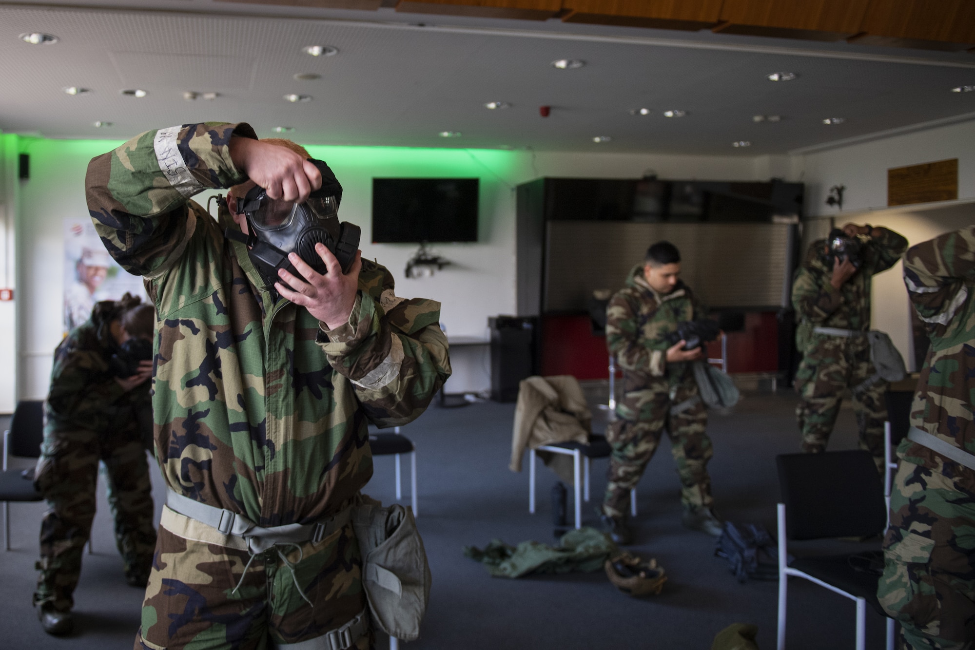 U.S. Air Force Airmen from the 702nd Munitions Support Squadron don their M50 gas masks as part of a timed Mission Oriented Protective Posture gear exercise at the 702nd MUNSS, April 13, 2021. Airmen must have their masks on and properly sealed in nine seconds or fewer, before a chemical, biological, radiological or nuclear attack begins to affect the body. (U.S. Air Force photo by Senior Airman Ali Stewart)