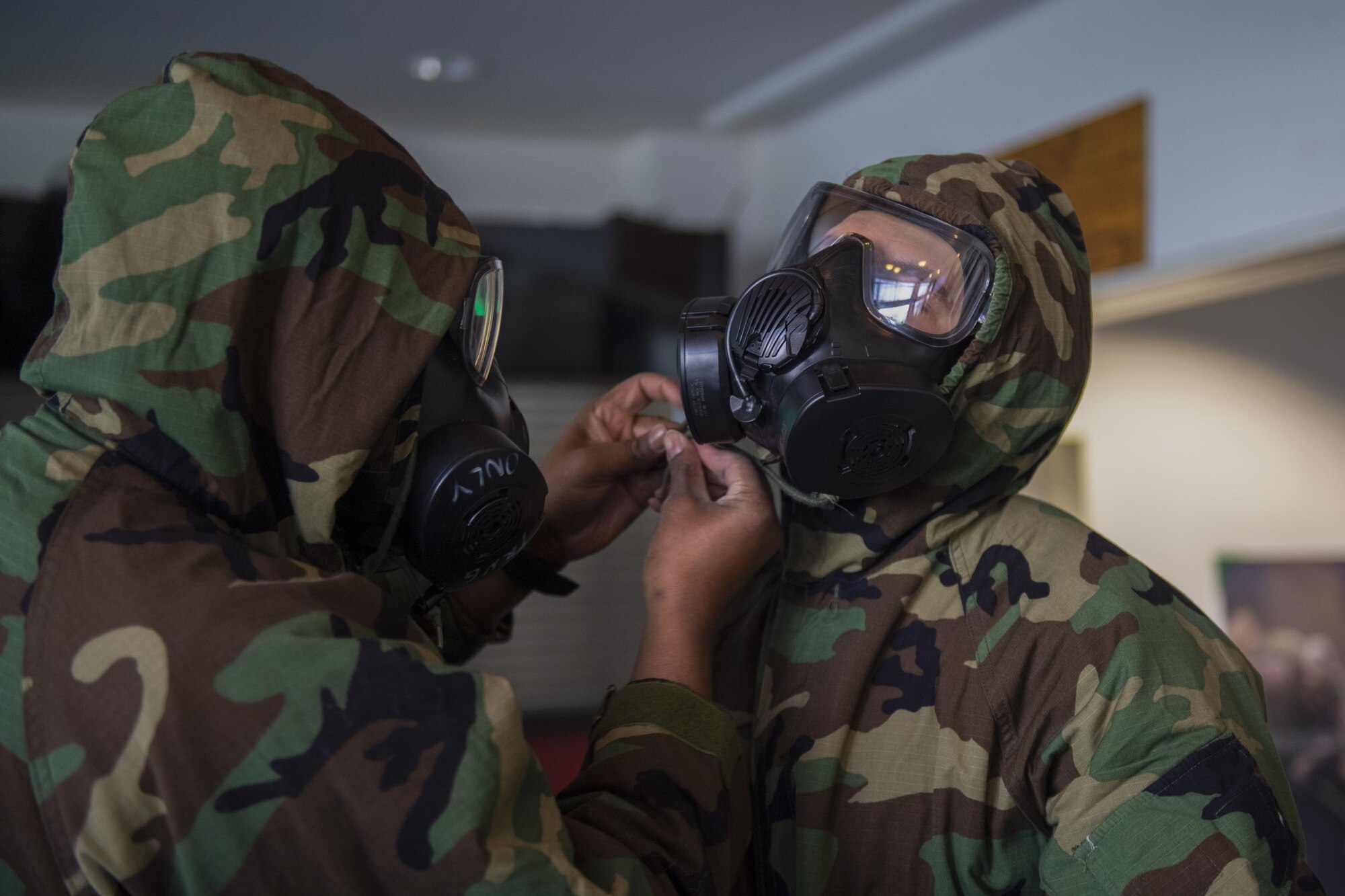 Two U.S. Air Force Airmen from the 702nd Munitions Support Squadron perform a buddy check on one another during chemical, biological, radiological and nuclear training at the 702nd MUNSS, April 13, 2021. Buddy checks are performed while Airmen are in full Mission Oriented Protective Posture gear to ensure there are no potential leaks in the MOPP suit or gas mask. (U.S. Air Force photo by Senior Airman Ali Stewart)