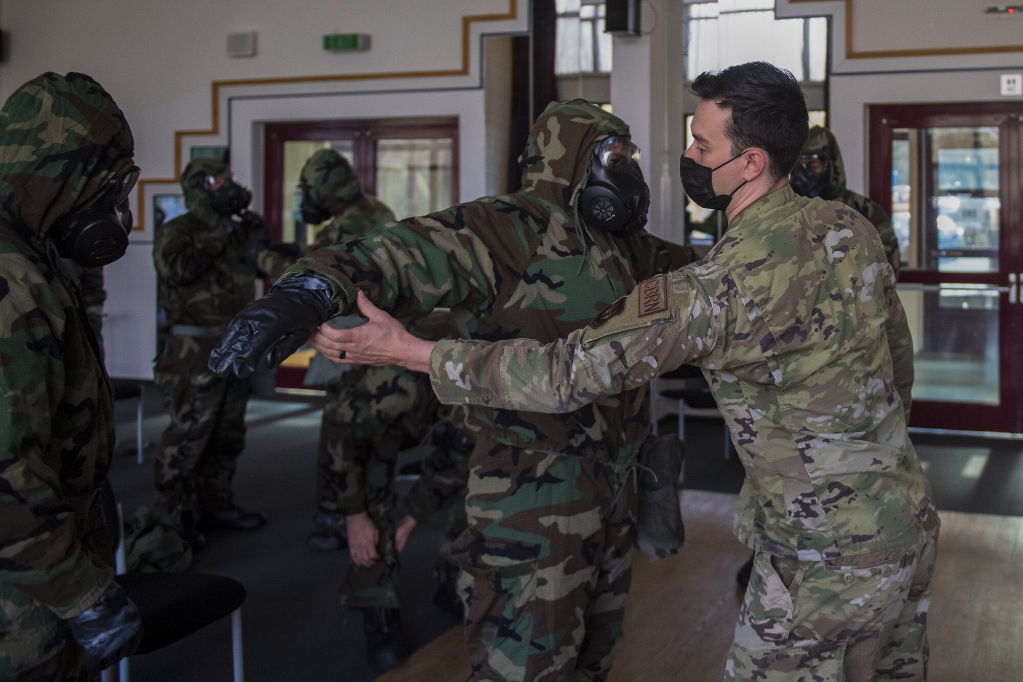 U.S. Air Force Staff Sgt. James Hargraves, right, 52nd Civil Engineer Squadron emergency manager, inspects a 702nd Munitions Support Squadron Airman's Mission Oriented Protective Posture gear during chemical, biological, radiological and nuclear response training at the 702nd MUNSS, April 13, 2021. Hargraves and other members of the mobile CBRN training team from Spangdahlem Air Base traveled to teach Airmen at the 702nd MUNSS, a geographically separated unit of the 52nd Fighter Wing. (U.S. Air Force photo by Senior Airman Ali Stewart)