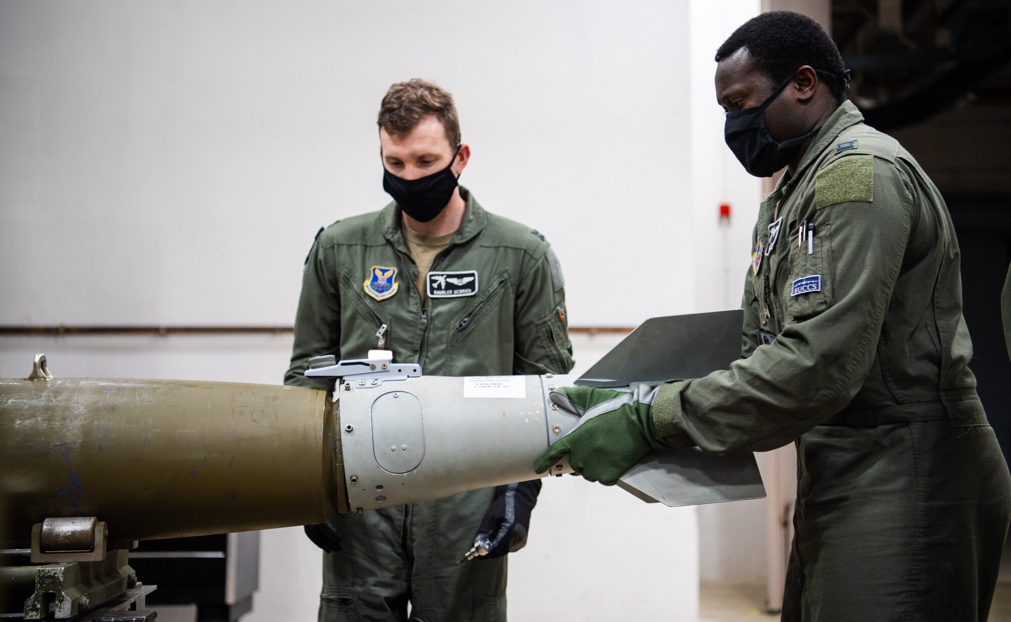 Capts. Michael McBrien and Joseph Okai, 340th Weapons Squadron weapon instructors course students, assemble a training munition during a training bomb build at Barksdale Air Force Base, Lousiana, April 13, 2021. Airmen from the 340th WPS integrated with the 2nd Munitions Squadron to teach the students the components and procedures that go into assembling a bomb. (U.S. Air Force photo by Airman 1st Class Jacob B. Wrightsman)