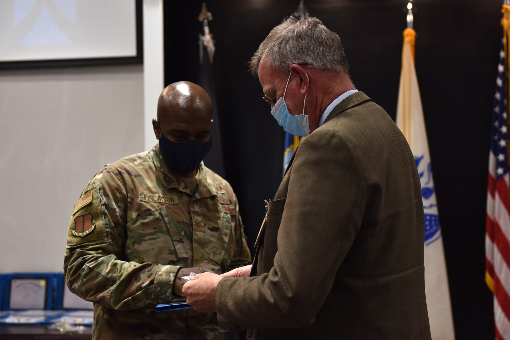 U.S. Air Force Col. James Finlayson, 17th Training Wing vice commander, presents Robert Bluthardt, Honorary Commander Alumni, a certificate at the Honorary Commander graduation in the Event Center on Goodfellow Air Force Base, Texas, April 9, 2021. Graduates were also given a pin and wing coin to thank them for their hard work during their time as Honorary Commanders. (U.S. Air Force photo by Staff Sgt. Seraiah Wolf)