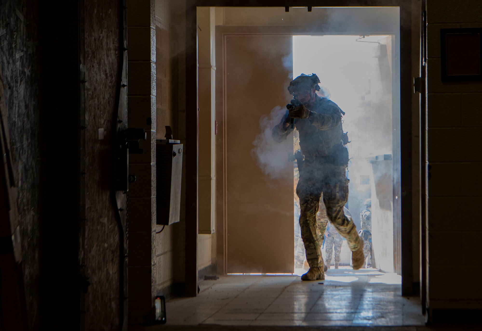 Airman enters building holding a rifle during training.
