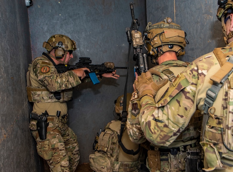 Airmen in a hallway holding rifles during a exercise.