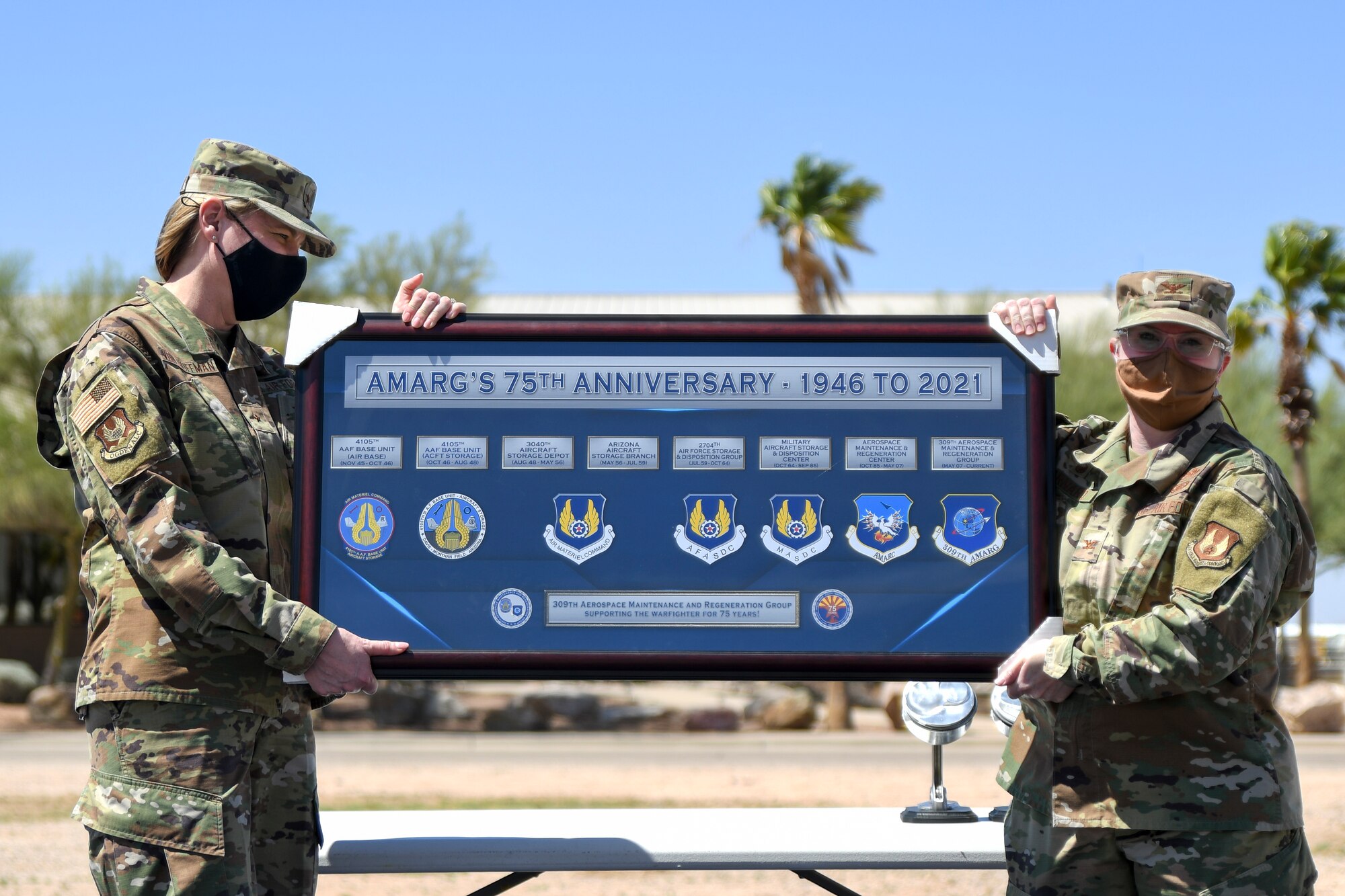 A picture of Brig. Gen. von Hoffman and Colonel Barnard holding up a plaque to commemorate the AMARG's 75th Anniversary.