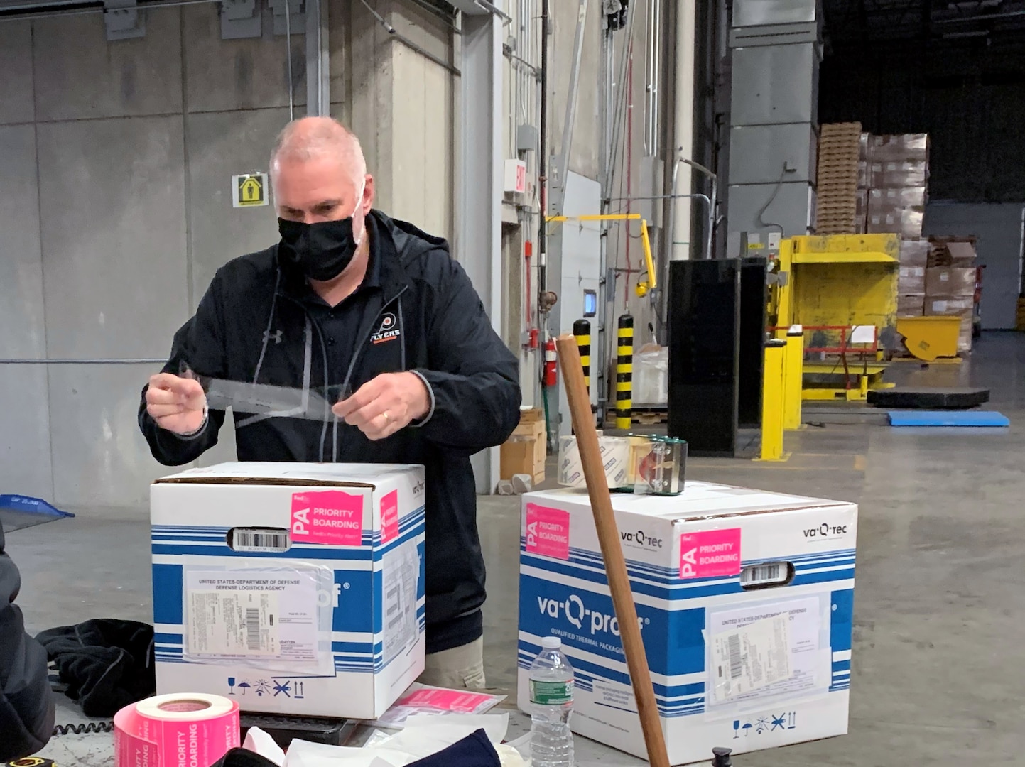 White man holds a label over top of a box he's preparing to ship.