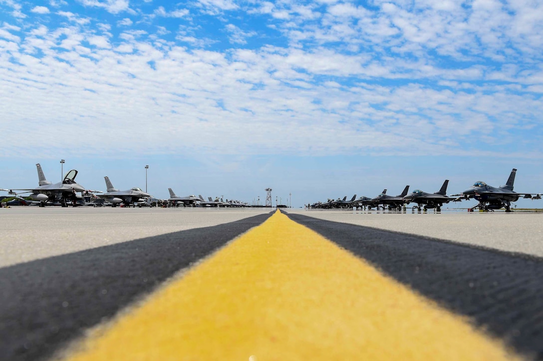 Air Force fighter jets sit parked on a runway.