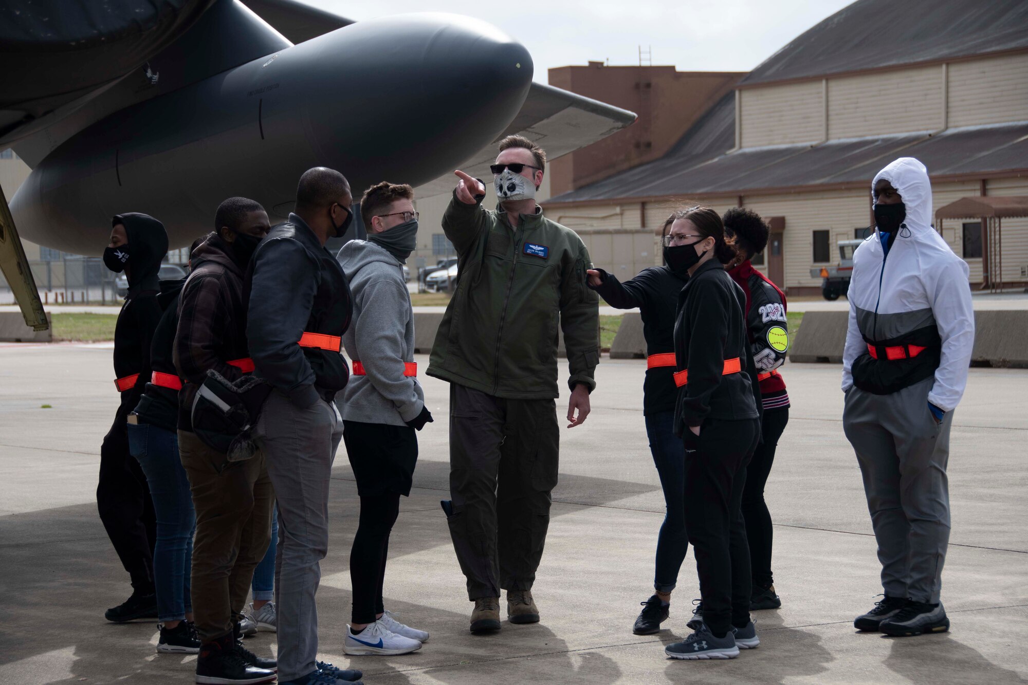 An Airman points at a B-52 as trainees look on.