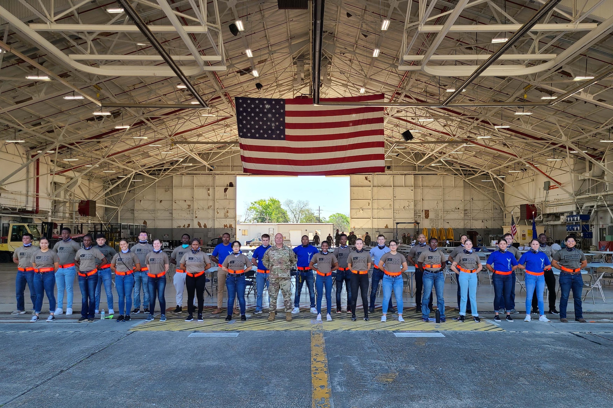 Air Force trainees pose in a group photo with a U.S. Flag overhead.