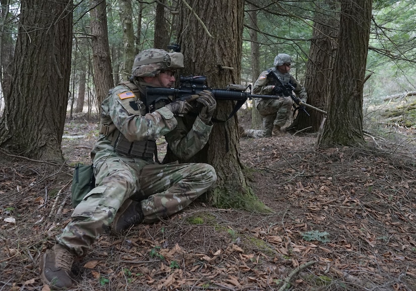 (Left) Spc. Collin Holmes, a Soldier from Bravo Company, 1st Battalion, 109th Infantry Regiment, 2nd Infantry Brigade Combat Team, leans against a tree for cover during movement to contact drills in a training area in Williamsport April 9, 2021. (U.S. Army photo by Sgt. 1st Class Matthew Keeler)