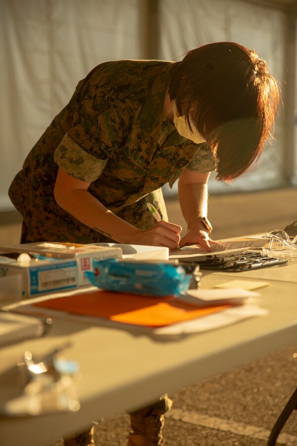 U.S. Navy Hospitalman 3rd Class Rachele WebbMcCoy from 2d Marine Division based out of Camp Lejeune, North Carolina, reviews a COVID-19 request form in the Memphis Community Vaccination Center in Memphis, Tennessee, April 12, 2021.