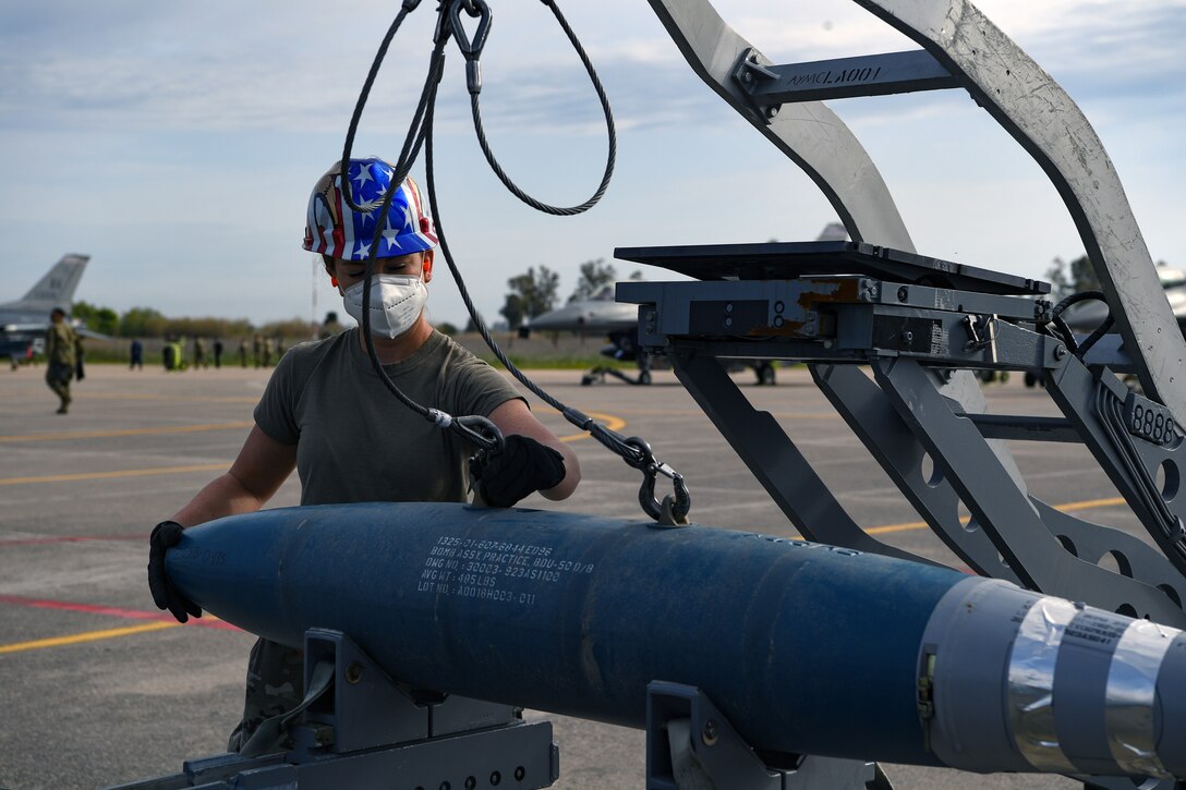 Senior Airman Hayley Peters, 31st Munitions Squadron (MUNS) conventional munitions crew chief unhooks an inert bomb from a bomb lift at Andravida Air Base, Greece, April 13, 2021. The 31st MUNS maintains and supports a combat ready stockpile, people, and equipment to support U.S. and NATO taskings. (U.S. Air Force photo by Airman 1st Class Thomas S. Keisler IV)