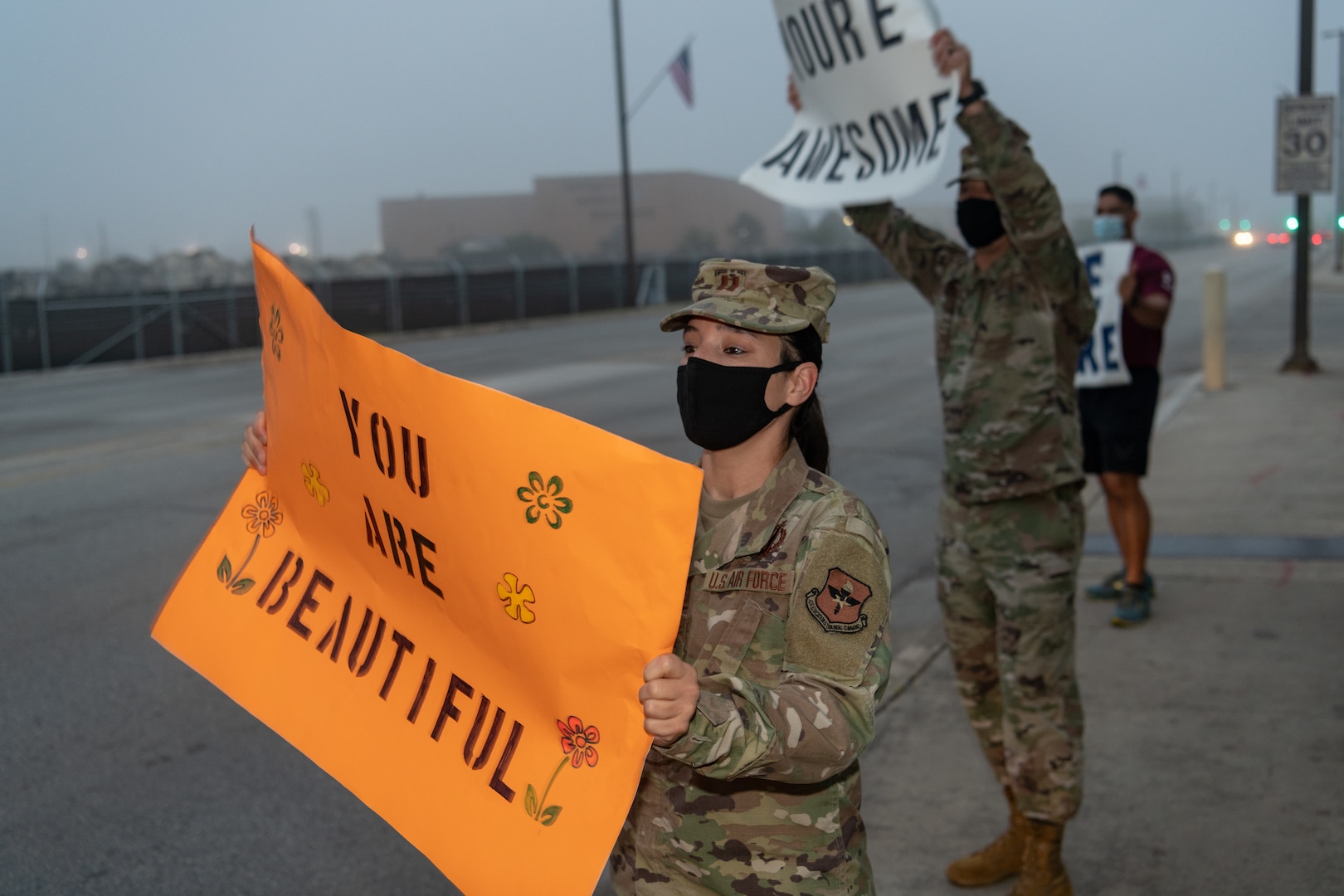 U.S. Air Force Capt. Brandy Dorrough (front), assistant director of the 323rd Training Squadron, and Tech Sgt. Lee Fast, interim 1st Sgt. for the 323rd Training Squadron, greet cars during the We Care Day event, April 16th, 2021, at Joint Base San Antonio-Lackland, Texas.