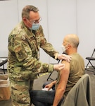 New York Air National Guard Lt. Col. John Reynolds, a registered nurse assigned to the 105th Airlift Wing, vaccinates John Giarratano at the Jacob K. Javits Convention Center in New York City April 12, 2021. The convention center serves as a mass vaccination site with more than 600 National Guard personnel assisting the state health department.