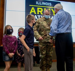 Family of newly promoted Lt. Col. Michael Barton, of Greenview, Illinois, children Bryer, Scarlett and Rhett, and uncle, Neil Tousley, tack on new rank during Barton’s promotion ceremony April 5 at Camp Lincoln in Springfield, Illinois.