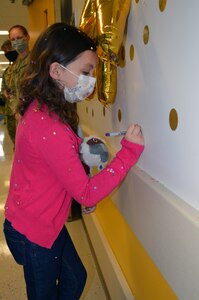 Seven-year-old Sailor Parker writes her name on a wall sticker after she rang the bell in the Brooke Army Medical Center Pediatric Hematology/Oncology Clinic April 1, signifying she won her battle against Acute Lymphocytic Leukemia.