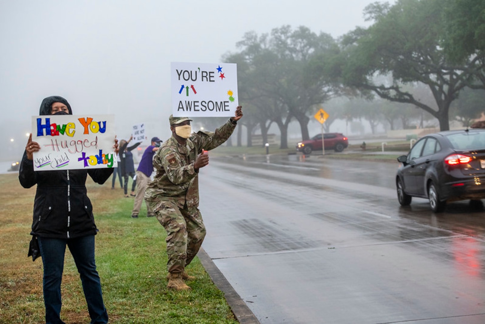 Command Master Chief Wendell Snider (right) holds a signs in support of the We Care Day event April. 16, 2021, at Joint Base San Antonio-Randolph, Texas. The event was in support of Month of the Military Child and Child Abuse awareness month.