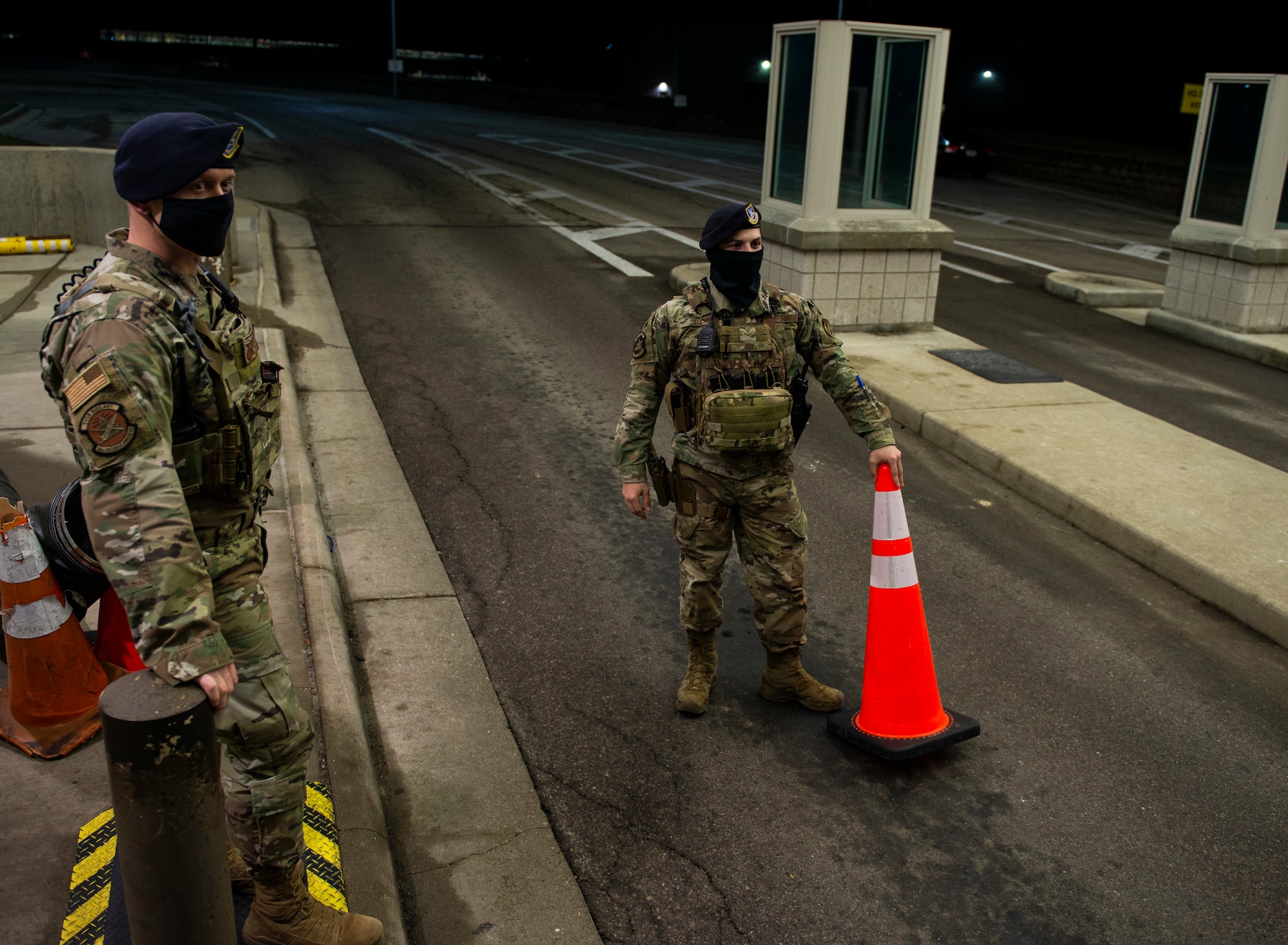 U.S. Air Force Staff Sgt. Jacob Swisher, 88th Security Forces Squadron base defense operations center controller, watches as a vehicle begins its approach to the gate as Airman 1st Class Jadon Dix, 88th SFS entry controllers and alarm monitor, prepares to remove a traffic cone at gate 19B, March 16, 2021 at Wright-Patterson Air Force Base, Ohio. Security Forces members are responsible for providing base defense, as well as providing law enforcement on the installation. (U.S. Air Force photo by Wesley Farnsworth)