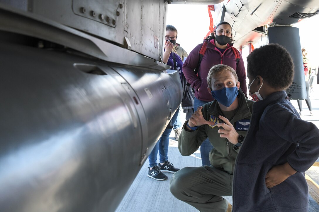 An airman talks with a child standing next to an aircraft.