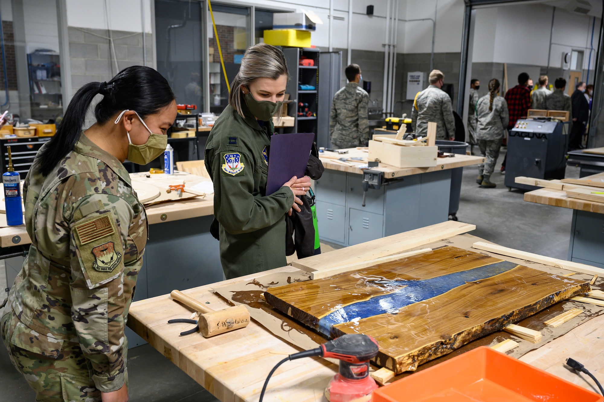 First Lt. Denise Guiao-Corpuz, 341st Missile Wing public affairs officer, left, and Capt. Madelaine Sawyer, 341st Missile Wing commander’s executive, admire a student-made table April 16, 2021, at Great Falls High School, Mont.