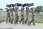 JOINT BASE SAN ANTONIO-CHAPMAN TRAINING ANNEX, Texas—Chief Master Sgt. Todd M. Popovic, Special Warfare Training Wing, or SWTW, command chief, leads a formation in memorial pushups after a memorial log carry for fallen airman, Lt. Col. William Schroeder, at the SWTW located on Joint Base San Antonio-Chapman Training Annex, or JBSA-CTA, Apr. 8, 2021.