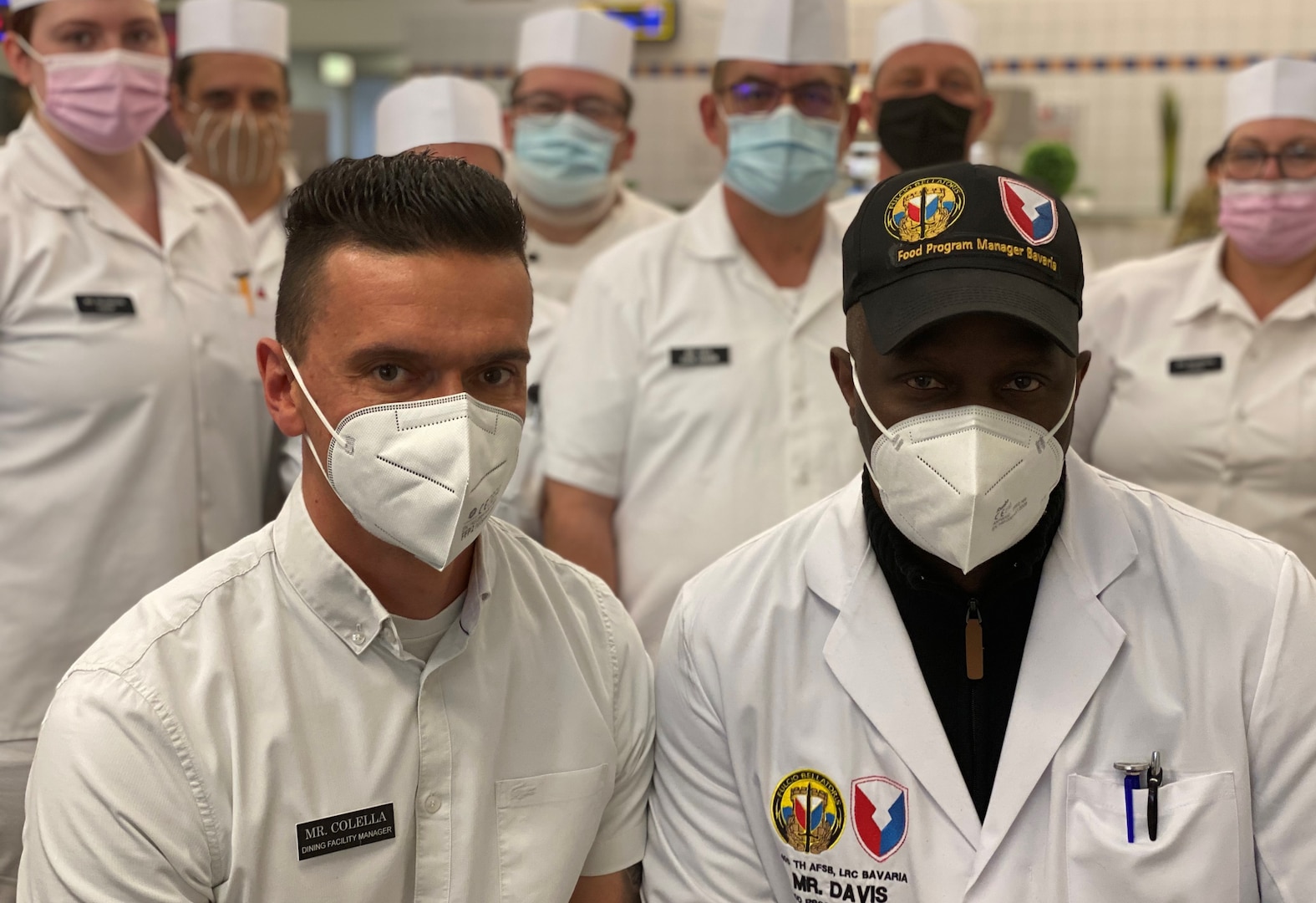 Michael Davis, the food service program manager for Logistics Readiness Center-Bavaria, and Adriano Colella, the CSM Lawrence Hickey Warrior Restaurant dining facility manager, pose for a photo with few food service program employees at the DFAC in Grafenwoehr Training Area. Davis said more than 300 food service program employees are assigned to the 405th Army Field Support Brigade’s LRC-Bavaria.