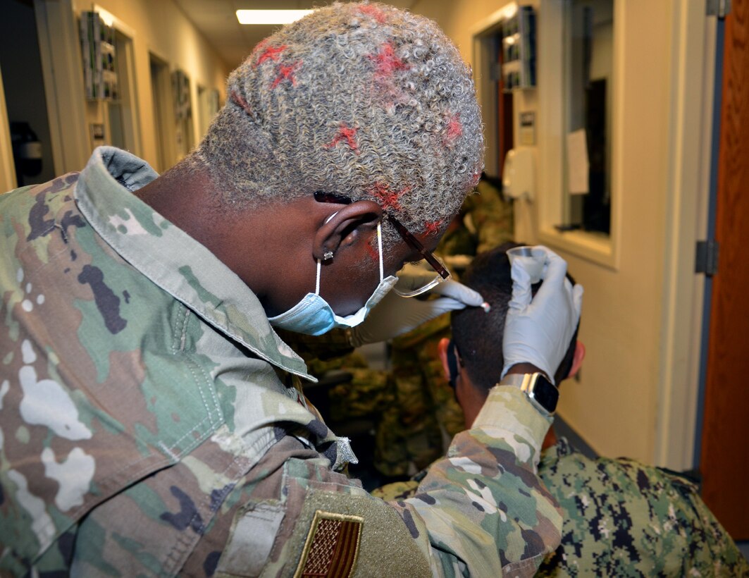 Air Force Senior Airman Jamila Basit, a student in the Neurodiagnostic Technician program at the Medical Education and Training Campus at Joint Base San Antonio-Fort Sam Houston, practices the electrode application method required for performance of the electroencephalogram, or EEG, on fellow student Navy Seaman Marcus Falcon.