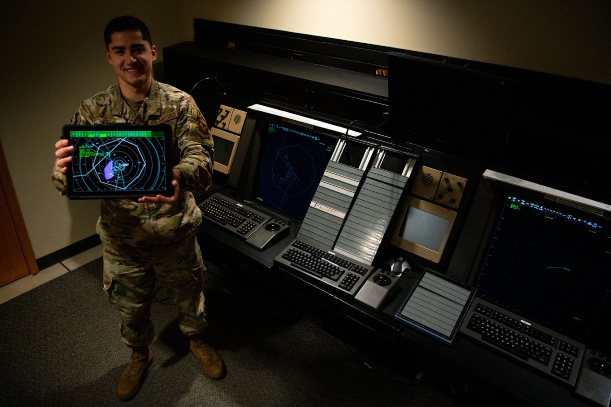 Senior Airman Christopher Daniel, a 28th Operation Support Squadron air traffic control (ATC) trainer, displays the new cloud-based training system in front of the old ATC training simulators at Ellsworth Air Force Base, S.D., April 15, 2021