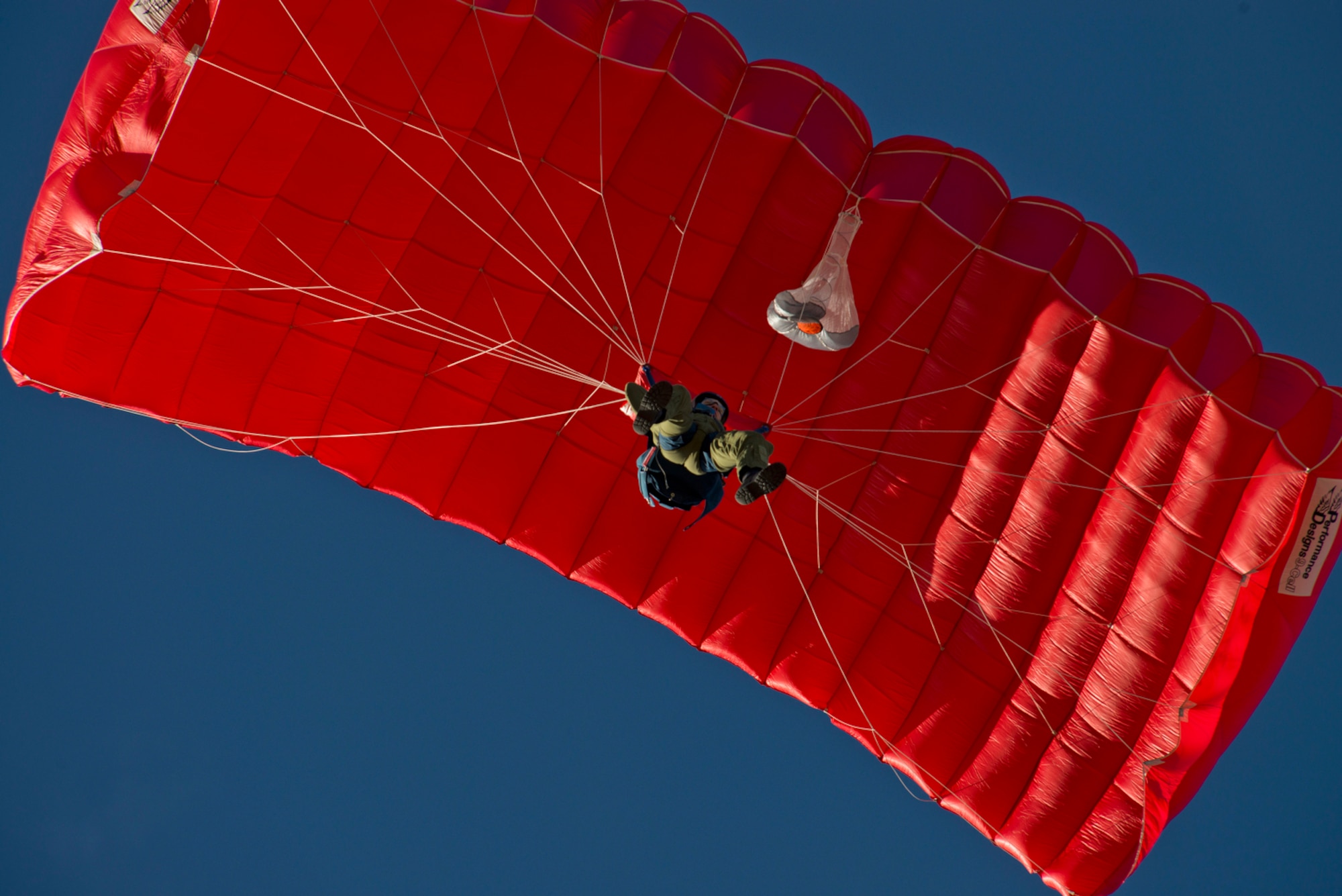 A U.S. Air Force Cadet prepares to land his initial parachute jump. Students are identified on their qualifying jumps by the red parachute canopies. (U.S. Air Force photo/Tech. Sgt. Bennie J. Davis III)