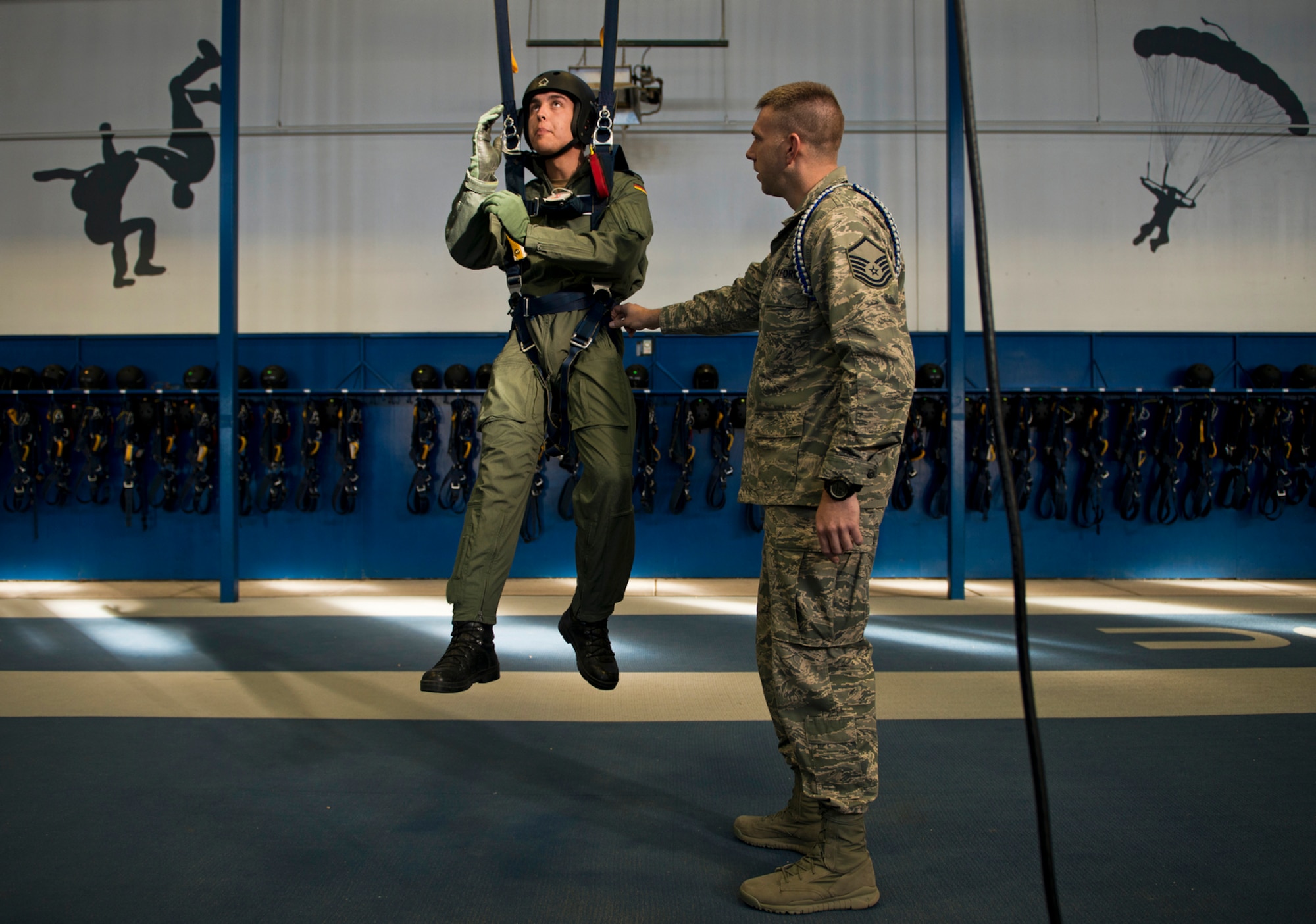 Master Sgt. David Siemiet, a jumpmaster with the Wings of Blue and AM490 instructor, prepares to teach a harnessed U.S. Air Force Academy International Cadet the proper techniques for troubleshooting a parachute canopy malfunction. AM490 is the only first-jump program in the world where students can make their first free-fall jump without assistance. (U.S. Air Force photo/Tech. Sgt. Bennie J. Davis III)