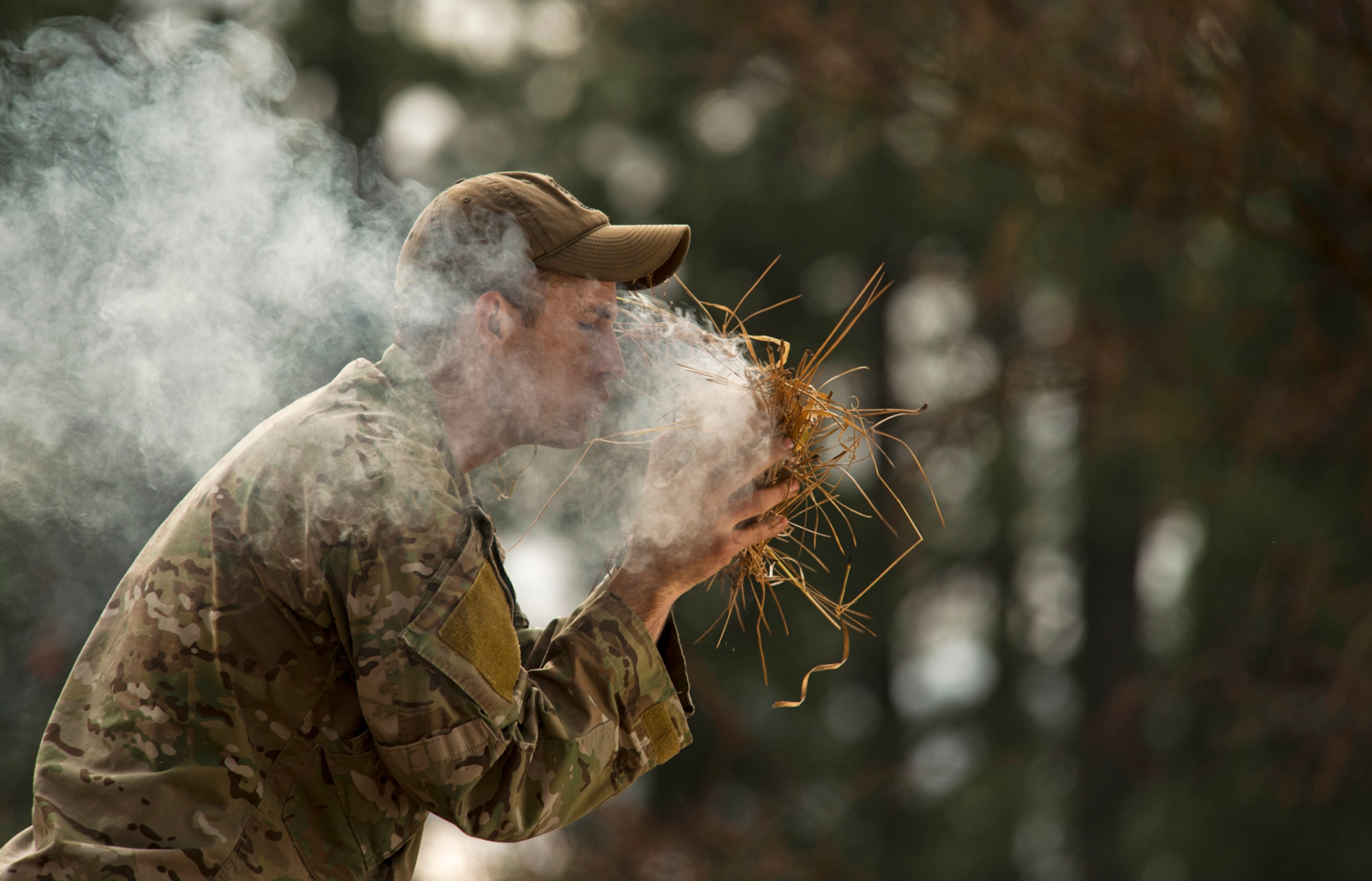 Senior Airman Joseph Collett, a survival, evasion, resistance and escape instructor, teaches the "bird's nest" technique of building a fire by igniting a small piece of flammable material with flint rocks and placing it inside a "nest" of weeds while blowing air into the nest to help the flame grow. (U.S. Air Force photo/Tech. Sgt. Bennie J. Davis III)