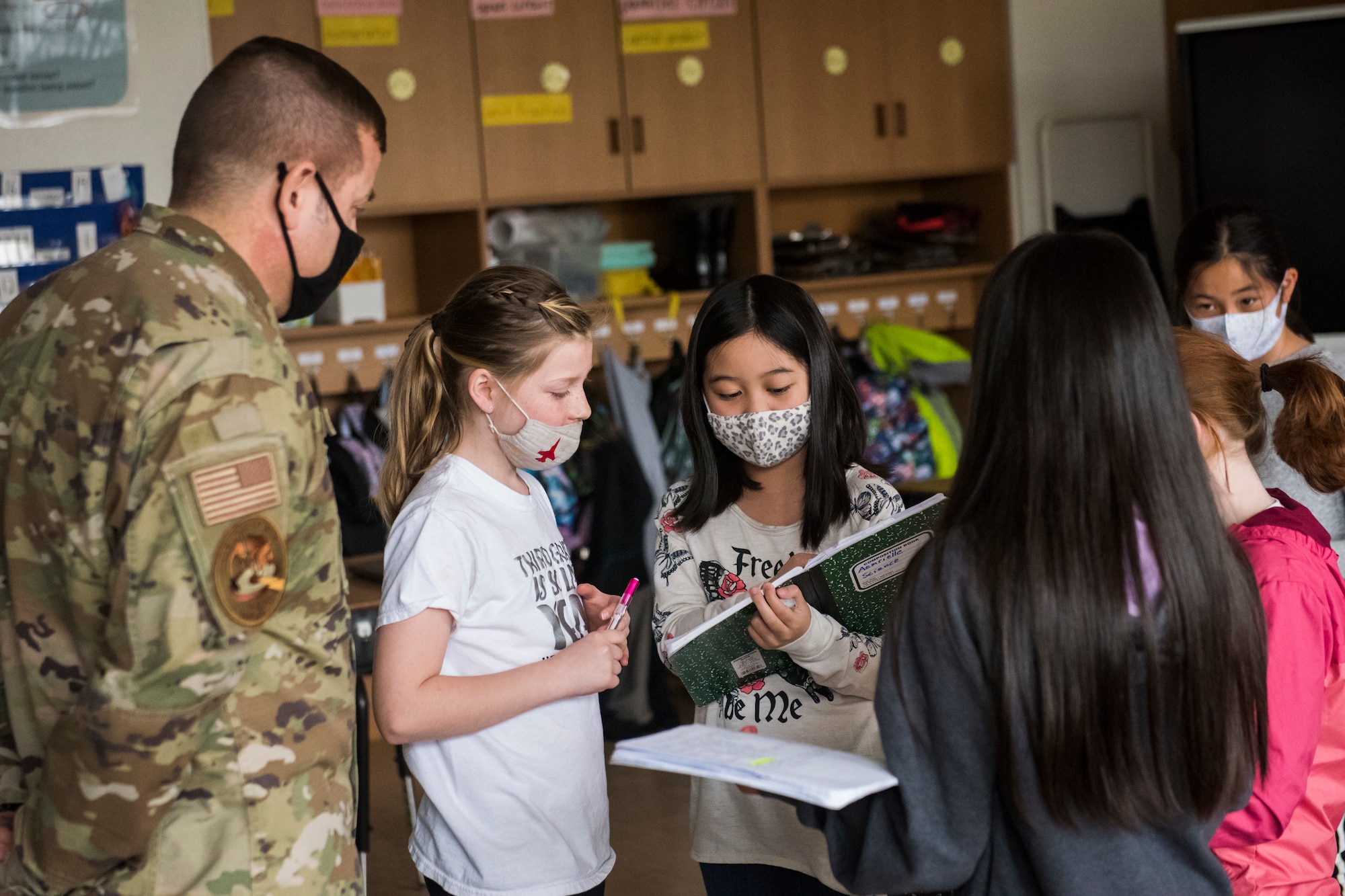 Man in uniform discusses with students trading notes.