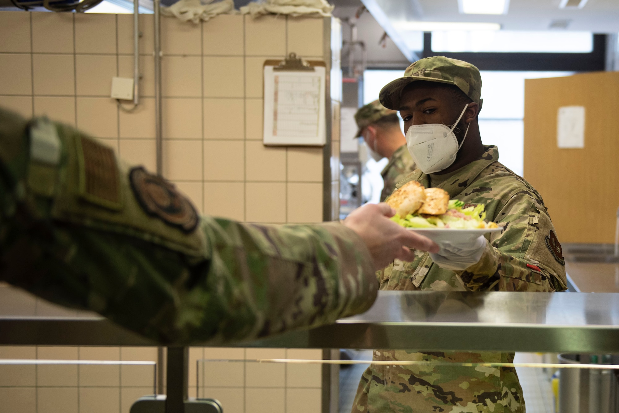 U.S. Air Force Senior Airman Andrew Logwood, 702nd Mission Support Flight dining facility storeroom manager, serves guests lunch in the dining facility, April 15, 2020, at the 702nd Munitions Support Squadron. During the COVID-19 pandemic, 702nd MUNSS MSF Airmen continued providing service, support and morale to 702 MUNSS Airmen by continuous training and listening to feedback from guests. (U.S. Air Force photo by Senior Airman Melody W. Howley)