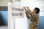 Service member takes down COVID-19 vaccination station signage