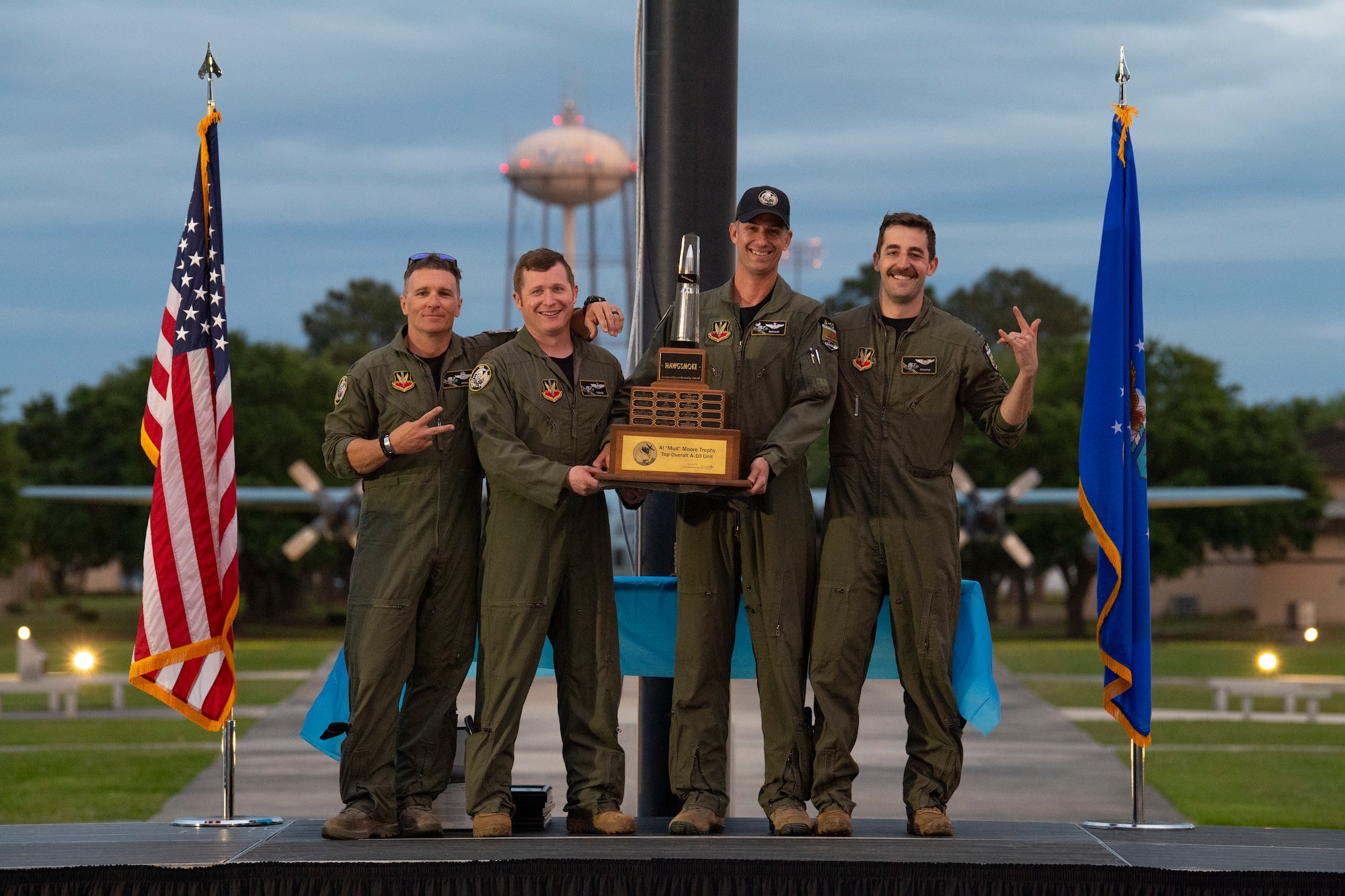 A photo of four Airmen posing, holding a trophy.