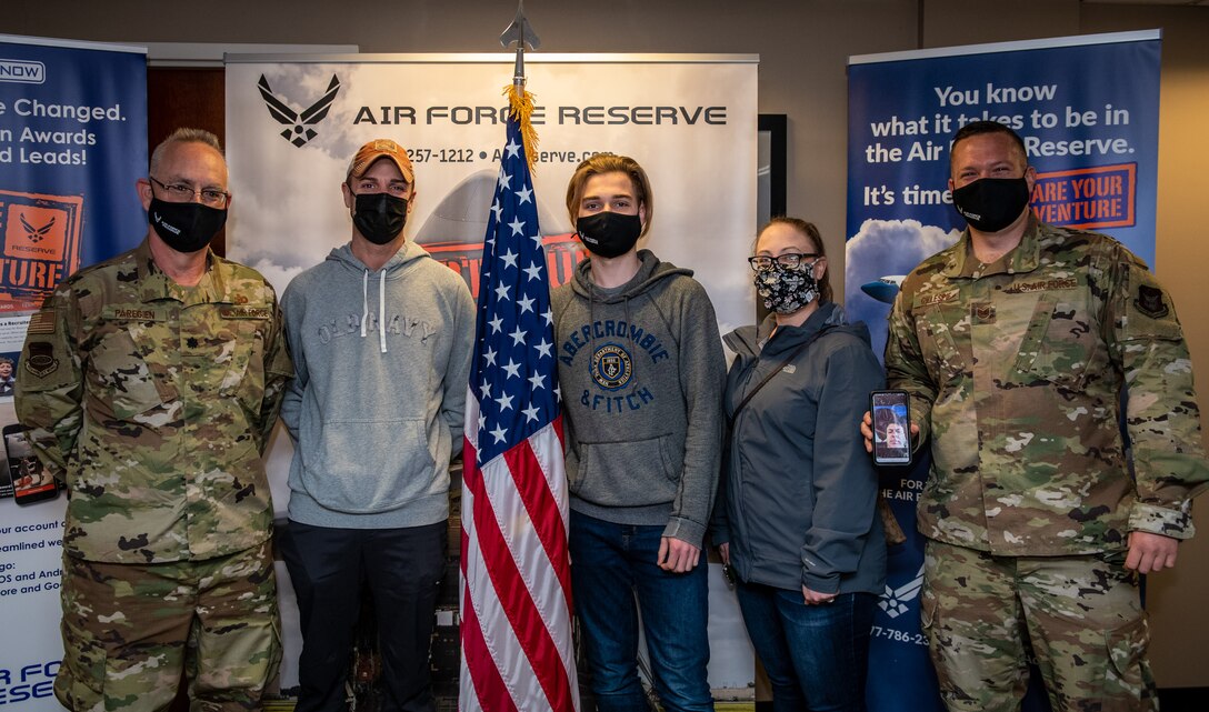 Bryce Ossman, newest recruit to join the 932nd Airlift Wing, poses with Lt. Col. Stan Paregien, left, Ossman's parents and Air Force recruiter Tech. Sgt. Tyler Gillespie, along with Ossman's grandfather virtually on a phone, after his oath of enlistment ceremony, April 8, 2021 at the 932nd AW Headquarters building, Scott Air Force Base, Illinois. (U.S. Air Force photo by Christopher Parr)