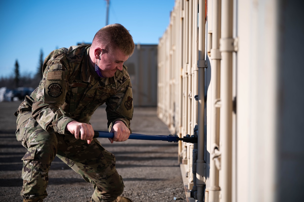 U.S. Air Force Airman Tel Jensen, a 354th Maintenance Squadron munitions stockpile management crew chief, removes a lock during a munitions barge at Eielson Air Force Base, Alaska, April 16, 2021.