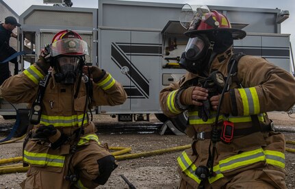 U. S. Air Force Staff Sgt. David Smith, left, and Andrew Sanchez, right, Joint Base San Antonio 902nd Civil Engineer Squadron lead firefighters, prepare for a forced entry scenario during a live fire training exercise, April 14, 2021, at Joint Base San Antonio-Randolph, Texas.