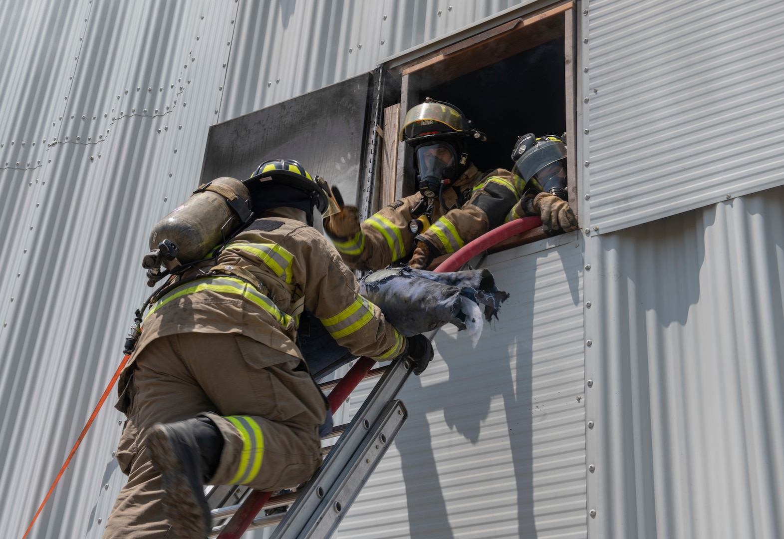 Joint Base San Antonio's 902nd Civil Engineer Squadron Fire Emergency Service members, and firefighters from Schertz and Cibolo fire departments, rescue a manikin from a building through a window during a live fire training exercise, April 14, 2021, at Joint Base San Antonio-Randolph, Texas.