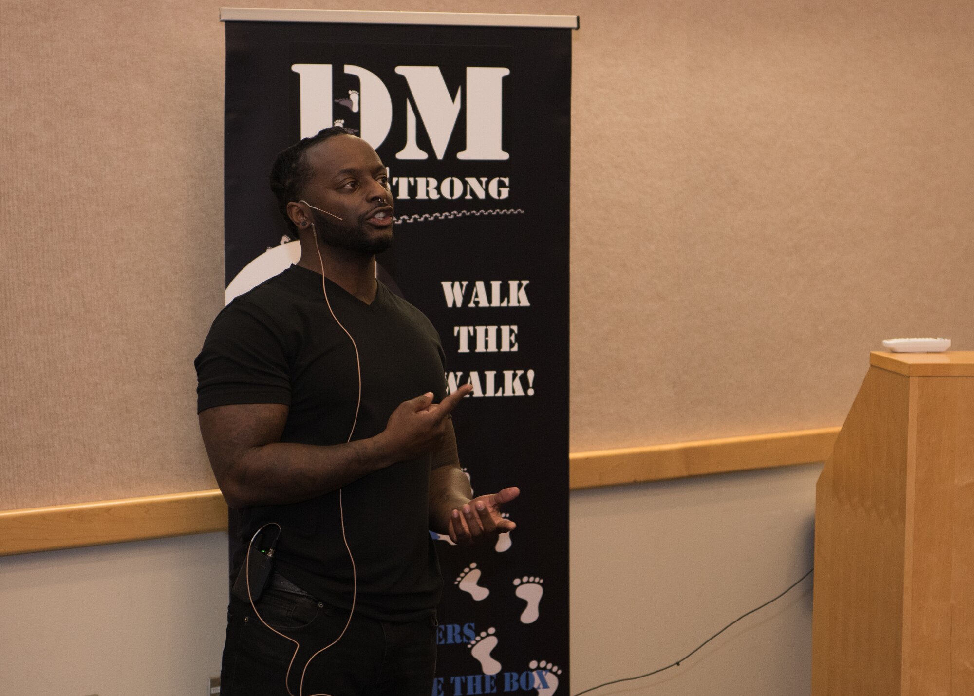 Edward Wilson, Difference Makers 10 Strong speaker, speaks to leadership in front of a DM 10 Strong Poster at the PDC auditorium.