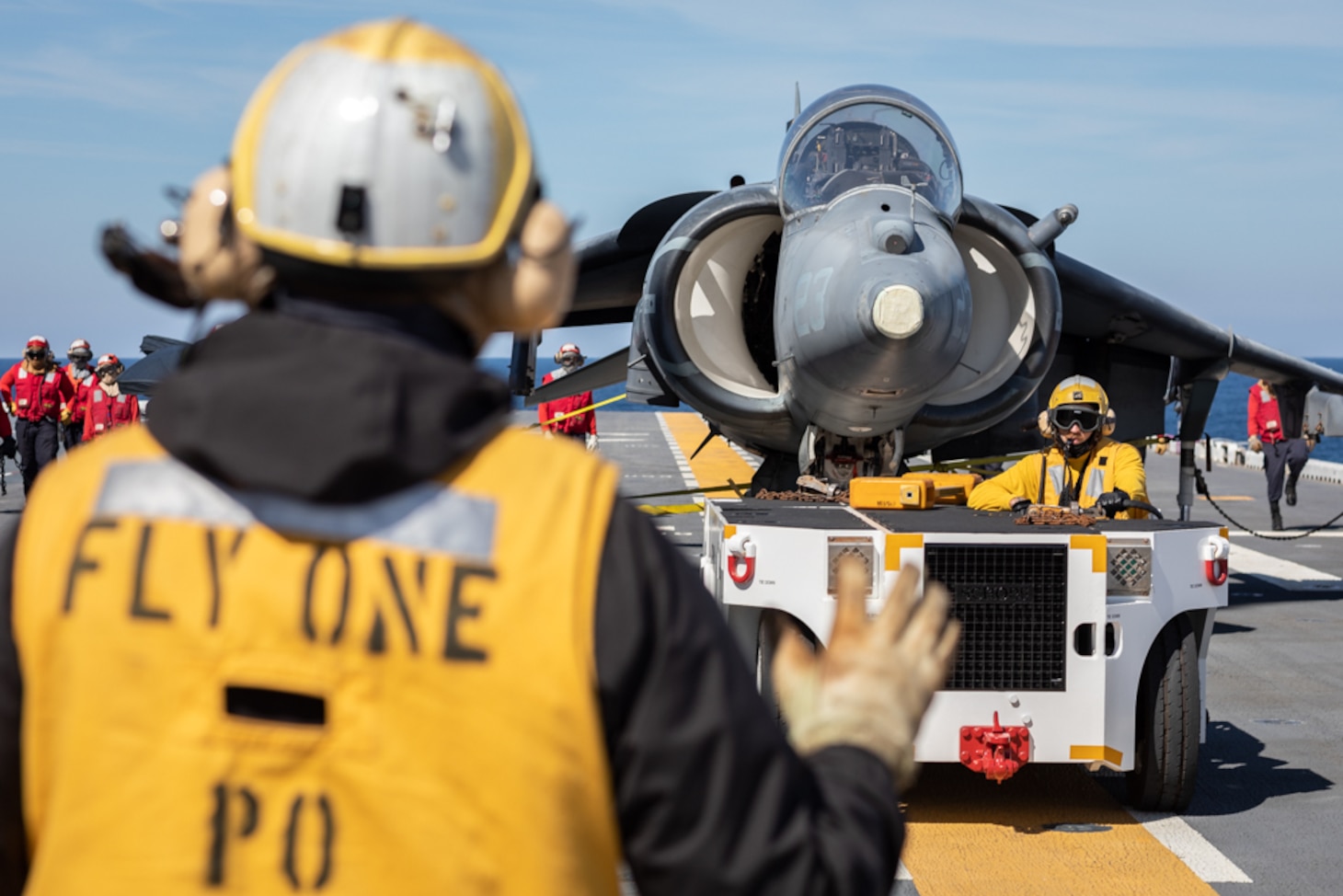 Aviation Boatswain's Mate (Handling) 2nd Class Jordan Larson guides a tow tractor driven by Aviation Boatswain's Mate (Handling) Airman Chad O'Connor during a drill on the flight deck.