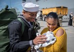 Service member looks at newborn in spouse's arms