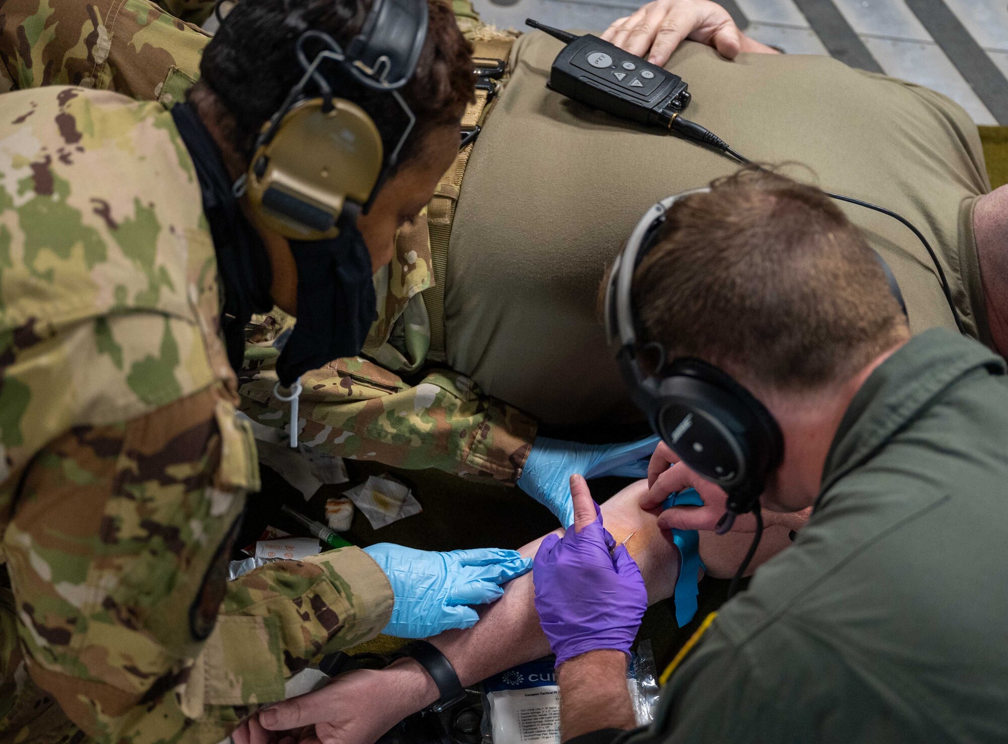 Capt. Kemeshia Greene, left, 775th Expeditionary Aeromedical Evacuation Flight officer in charge, and Staff Sgt. James Bittel, 775th EAEF aeromedical technician, administers a practice IV needle during a training flight over Maine, March 16, 2021. Aerospace Medical Service specialists provide essential care in multiple medical roles by assisting doctors and caring for patients in a wide range of situations.  (U.S. Air Force photo by Airman 1st Class Faith Schaefer)